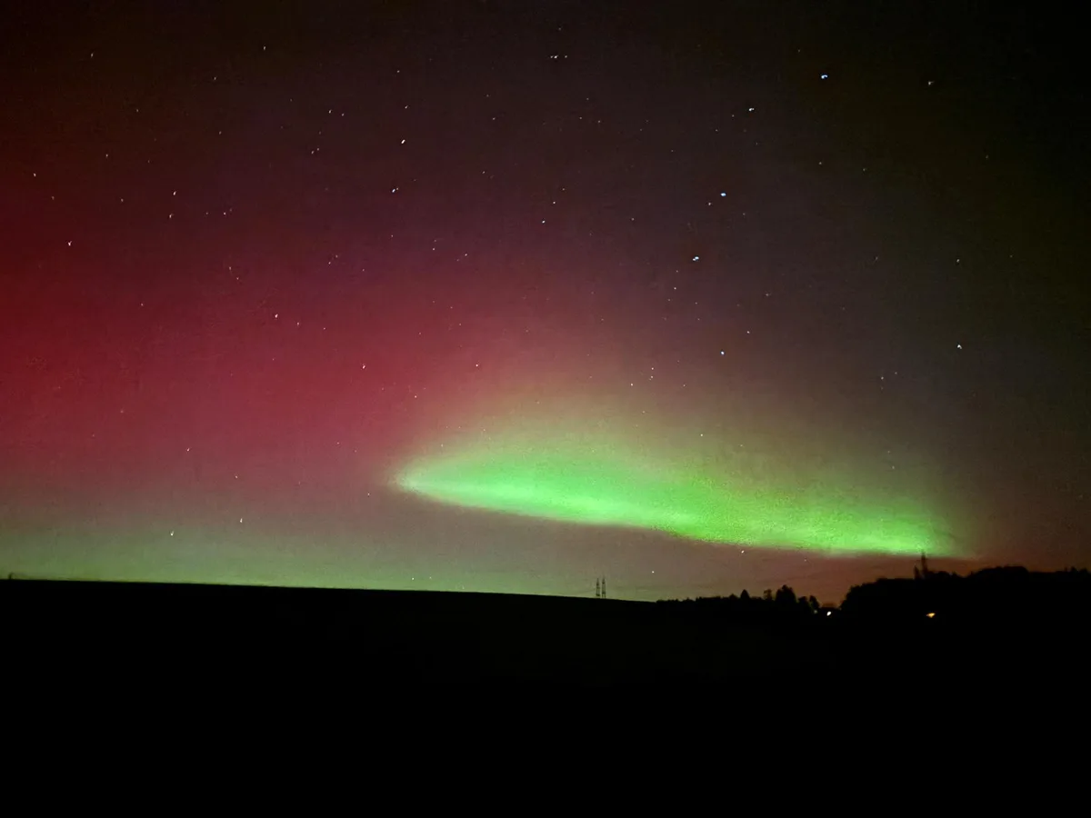 Man sieht grüne, violette und pinke Polarlichter am dunklen Nachthimmel.